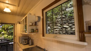 Une cuisine avec un mur en pierre apparent, un évier, un grille-pain et une bouilloire.