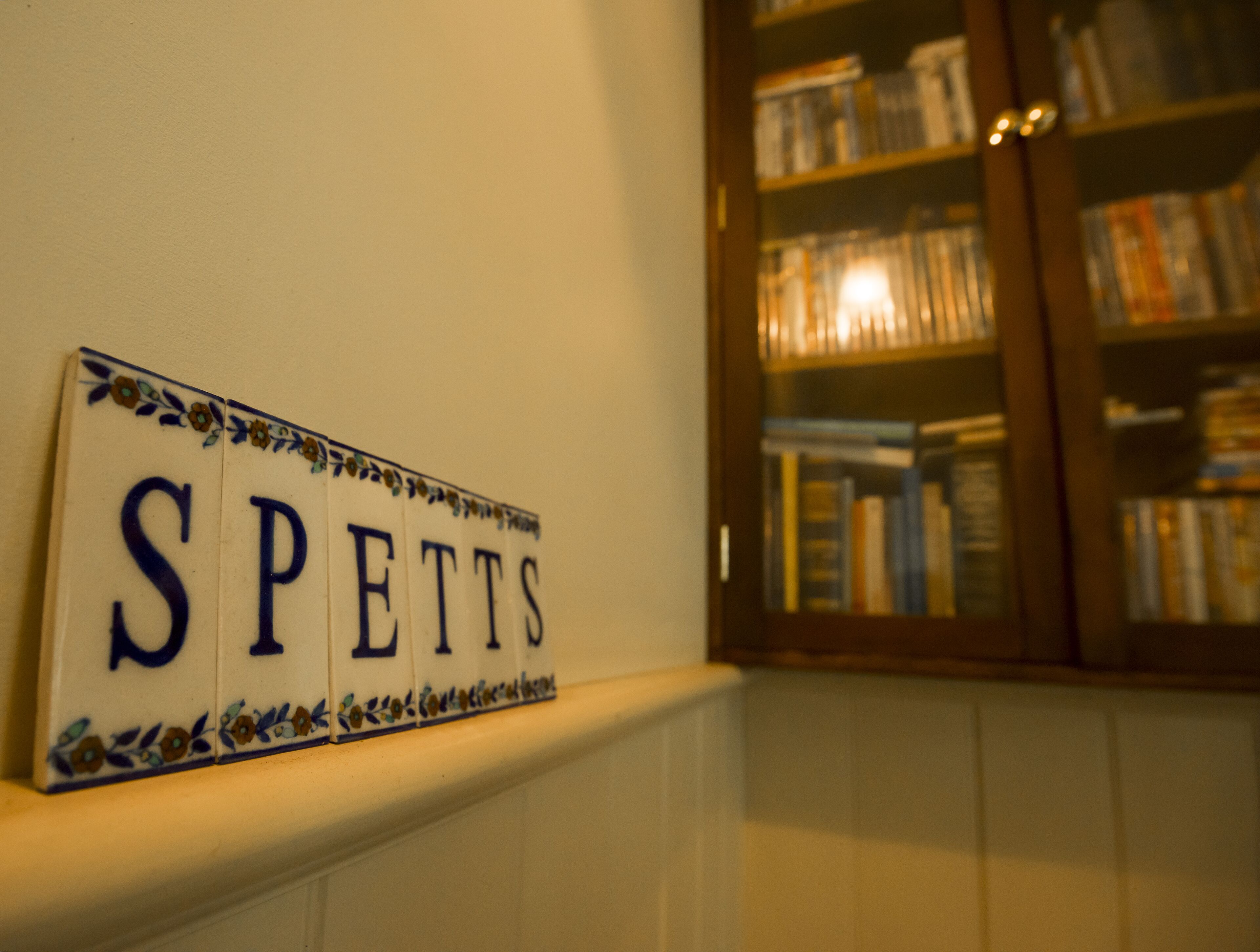 A wall-mounted sign with the word "SPETTS" surrounded by decorative floral patterns.