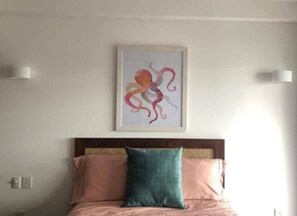 Une chambre à coucher avec un lit, une tête de lit et une œuvre d’art encadrée accrochée au mur.