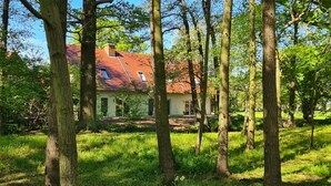 Une maison avec un toit rouge, entourée d’arbres et d’herbe.