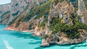 A coastal landscape with a prominent rocky cliff and clear turquoise waters.