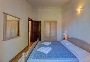 Un dormitorio con una cama, dos armarios, una mesita de noche con lámpara y un espejo en la pared.