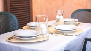 Mesa lista para comer, con platos, vasos y cubiertos.
