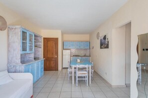 A compact living space with a kitchenette, a dining table, and a sofa.