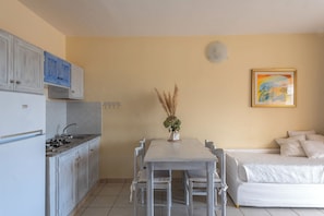 A compact kitchen with a dining table and chairs, a sofa, and a painting on the wall. - Fantastico Baia de Bahas Residence Sea View 2 Bedroom sleeps 6 (Marinella)