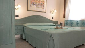 Un dormitorio con una cama individual, una mesita de noche, una lámpara de pared y un cuadro.
