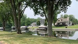 Une propriété au bord du lac, dotée d’un quai, de bateaux et d’une grande maison avec une véranda.