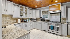 A kitchen with white cabinets, a granite countertop, a stainless steel stove, and a wooden ceiling. - Modern Antique 5BR Home w/ Expansive Master Suite (Norwich)