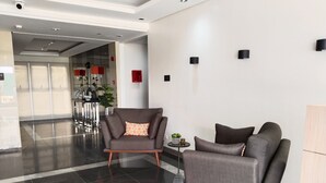 A modern lobby with a grey sofa, a smaller armchair, and a small table with plants. - Cozy Unit at SMDC Cheer Residences by Lee Portum (Marilao)
