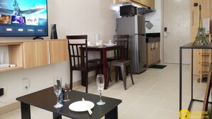 A modern kitchen with a dining area, a flat-screen TV, and a small Eiffel Tower model. - Cozy Unit at SMDC Cheer Residences by Lee Portum (Marilao)