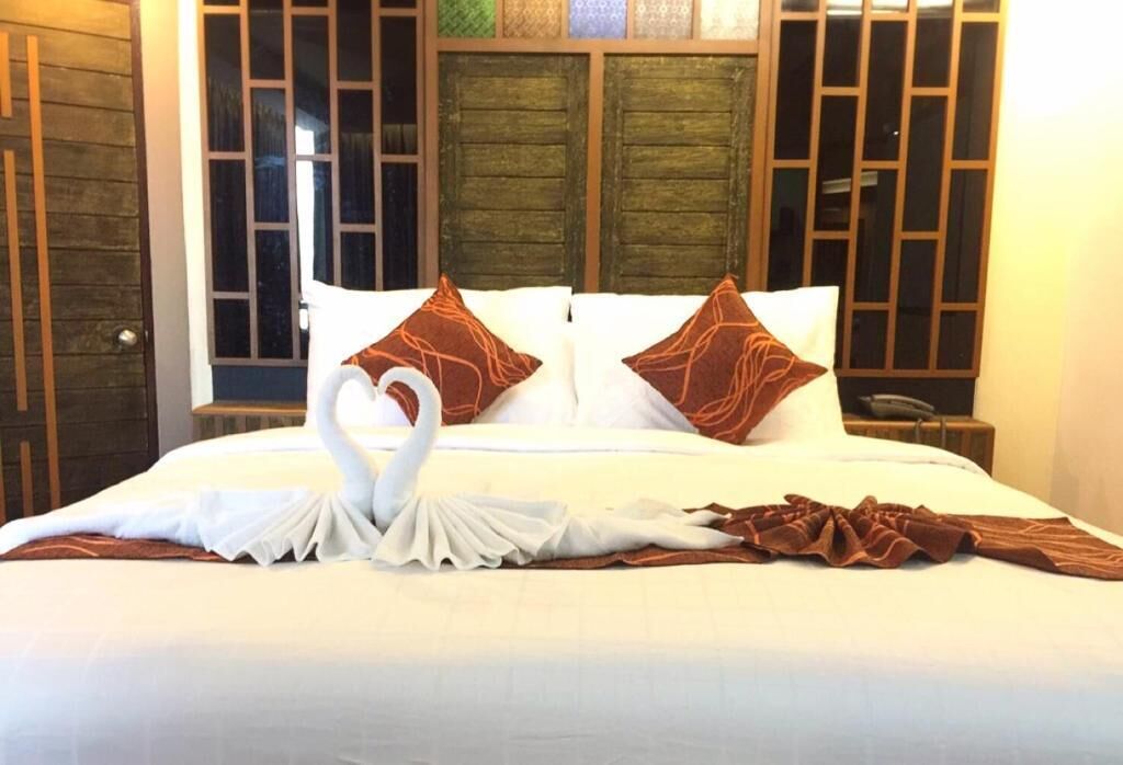 Cama bem arrumada com lençóis brancos e almofadas decorativas castanhas.