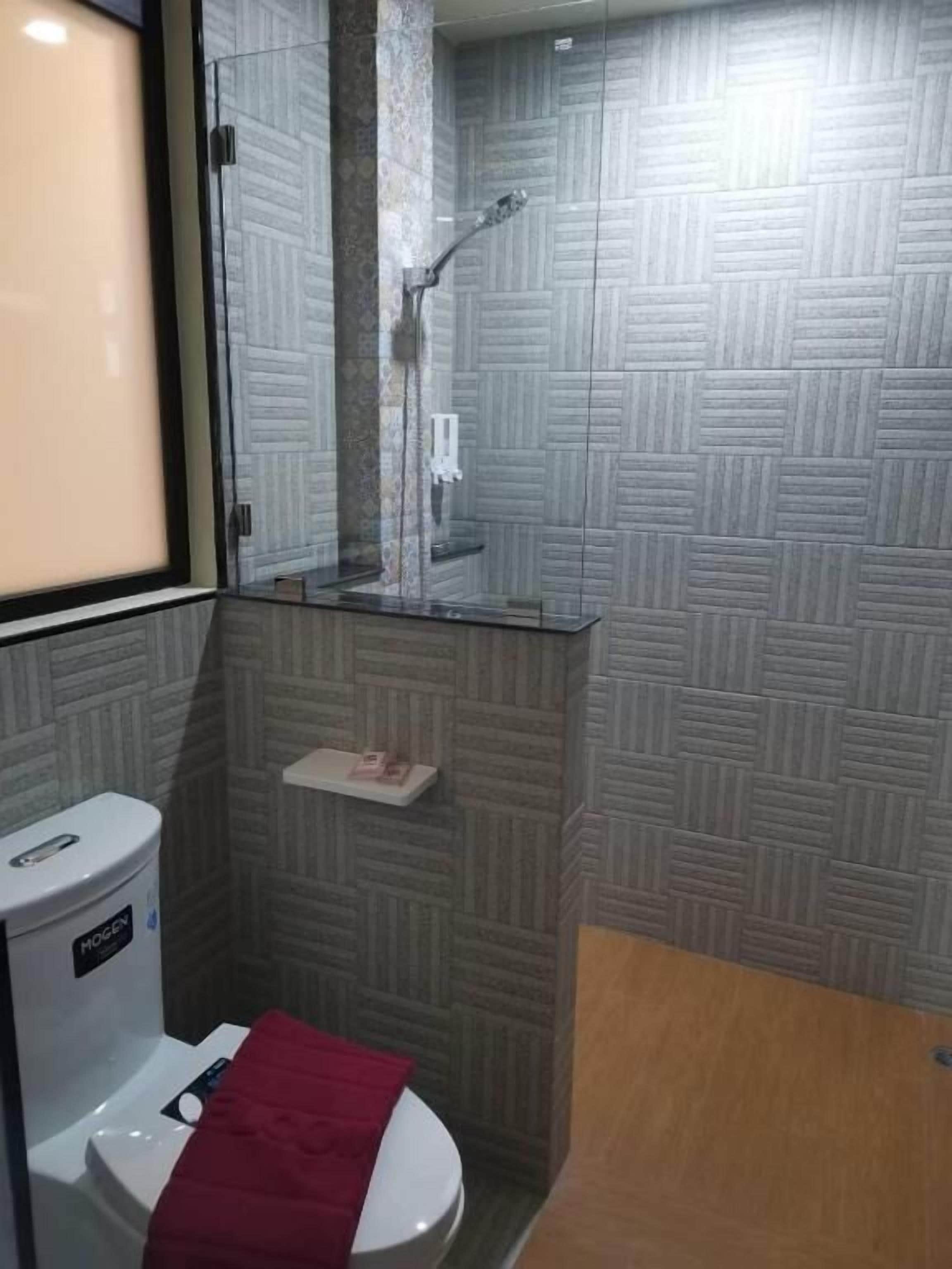 Un baño con inodoro, cabina de ducha de vidrio y pared con estampado.