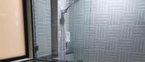 Un baño con inodoro, cabina de ducha de vidrio y pared con estampado.