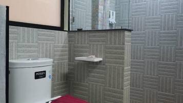 A bathroom with a toilet, a shower, and a tiled wall.