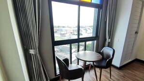Una habitación con un ventanal grande, una mesa redonda, dos sillas y una cortina.