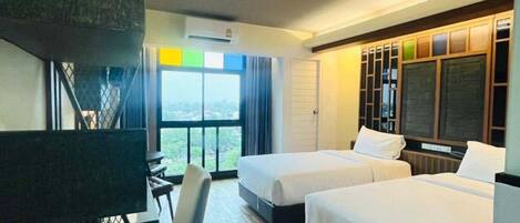 A hotel room with two beds, a desk, a chair, and a large window with a view.
