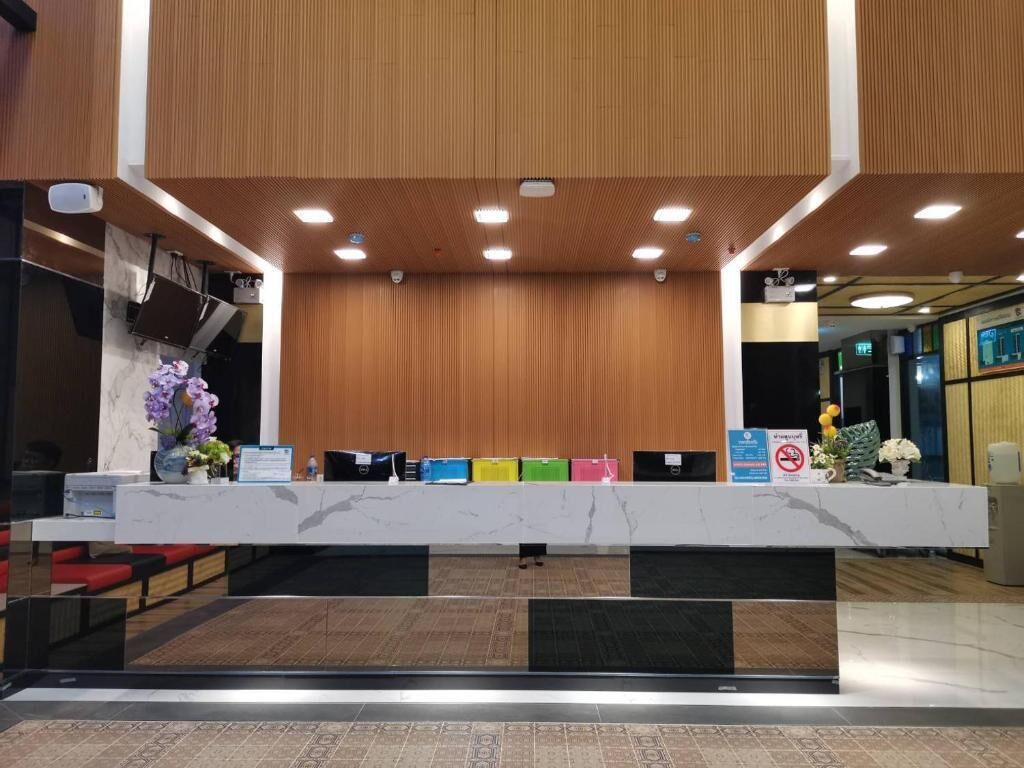 Vastaanottotiski, jossa on marmoritaso, seinissä puupanelointi ja tiskillä rivi värikkäitä kansioita.