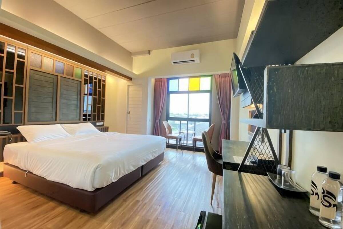 Una habitación de hotel con cama, escritorio, silla y vistas al exterior.