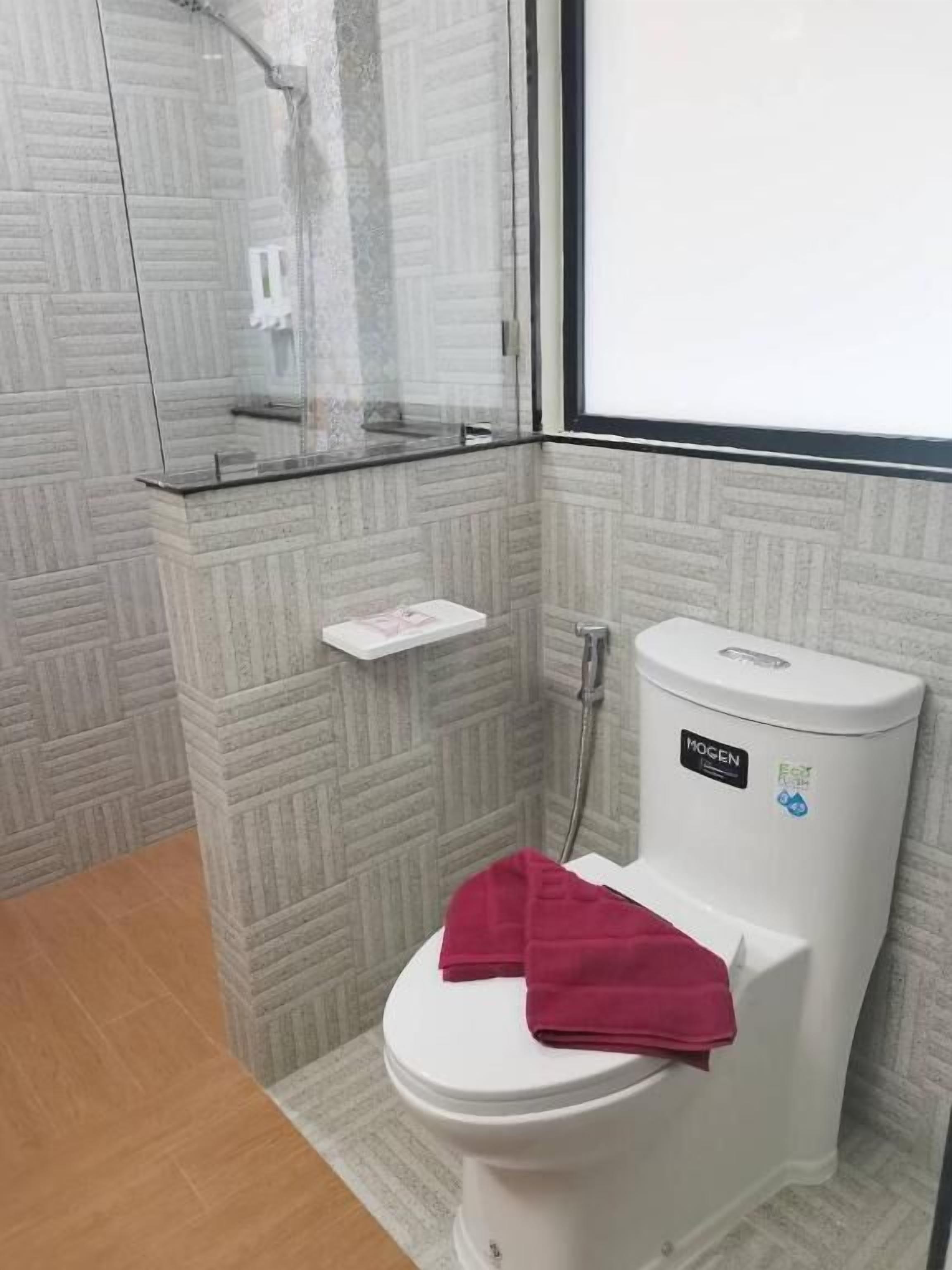 Une salle de bain comprenant des toilettes, une douche à parois de verre et un lavabo blanc.