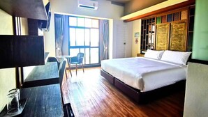 Una habitación de hotel con una cama, un escritorio, una silla y una ventana.