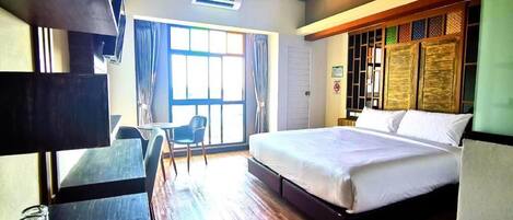 A hotel room with a bed, a desk, a chair, and a window.