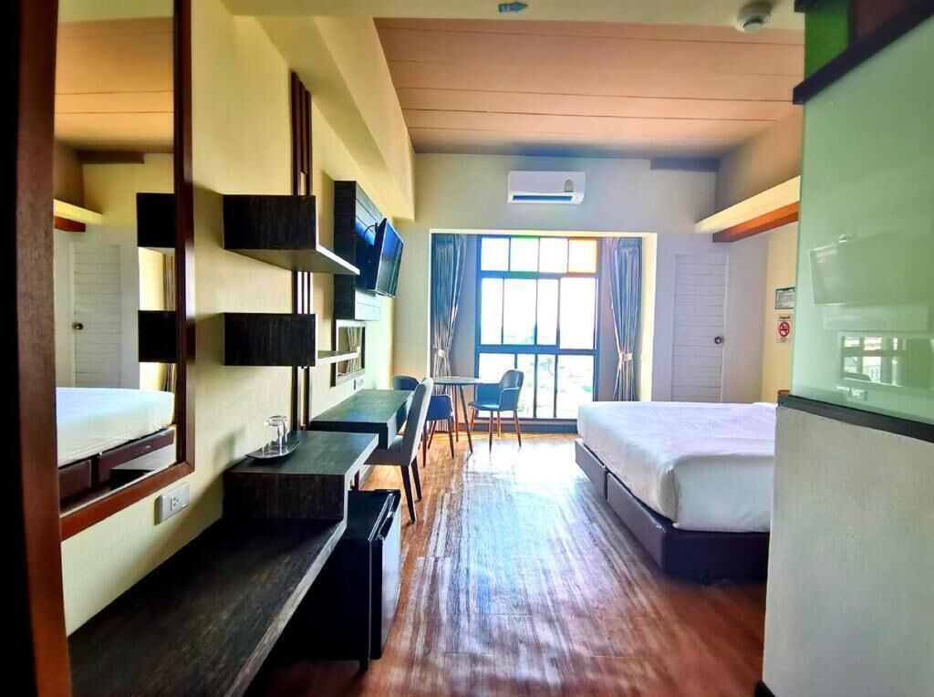 A compact hotel room with a bed, a desk, a chair, and a window with curtains.