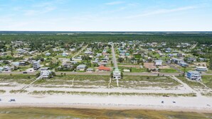 Luchtbeeld van een kustgebied met woningen, wegen en een strand.