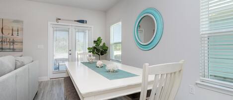 A dining area with a white table, teal placemat, and a white chair.