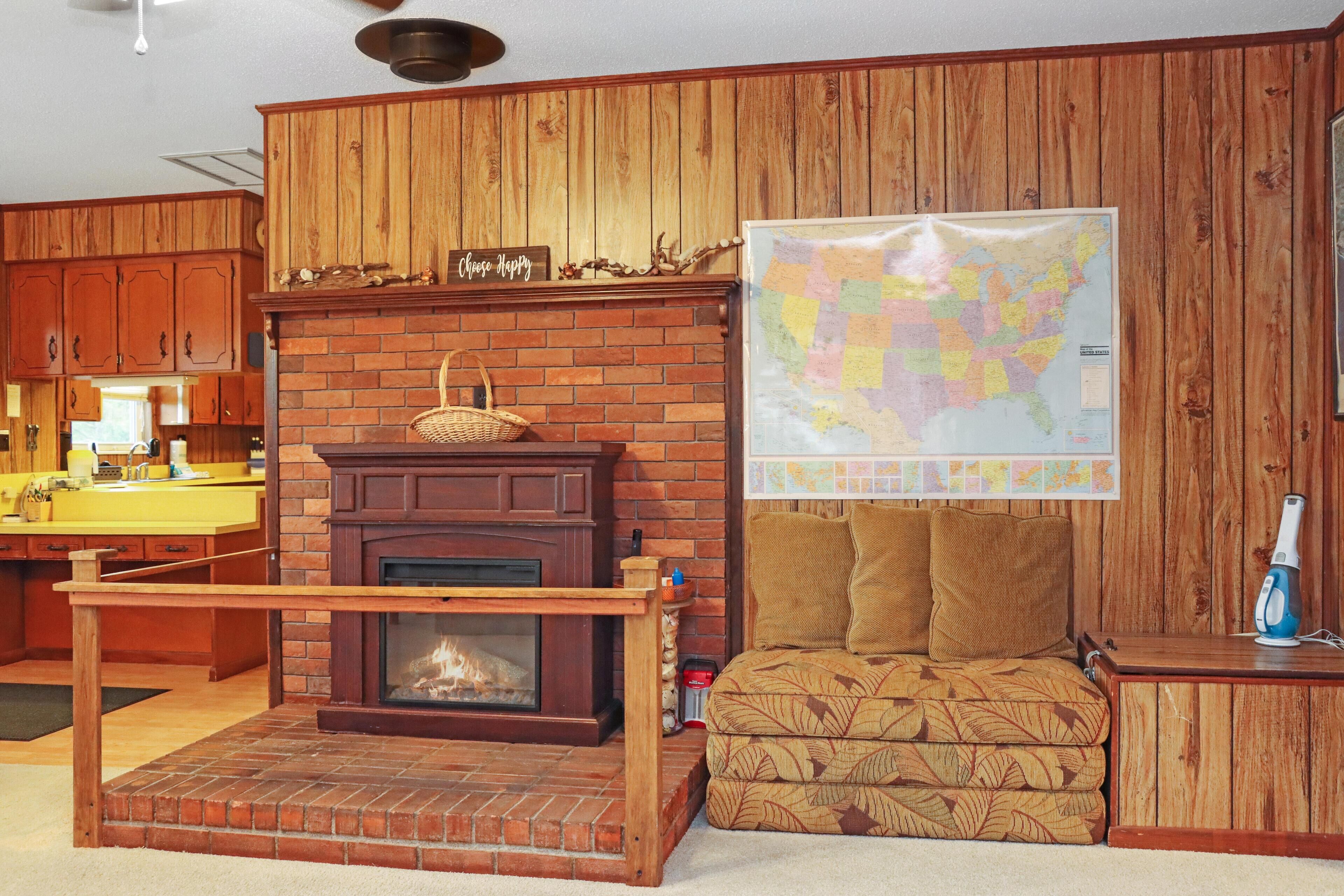 Ein gemütliches Wohnzimmer mit Kamin, einer Karte an der Wand und einer bequemen Couch.