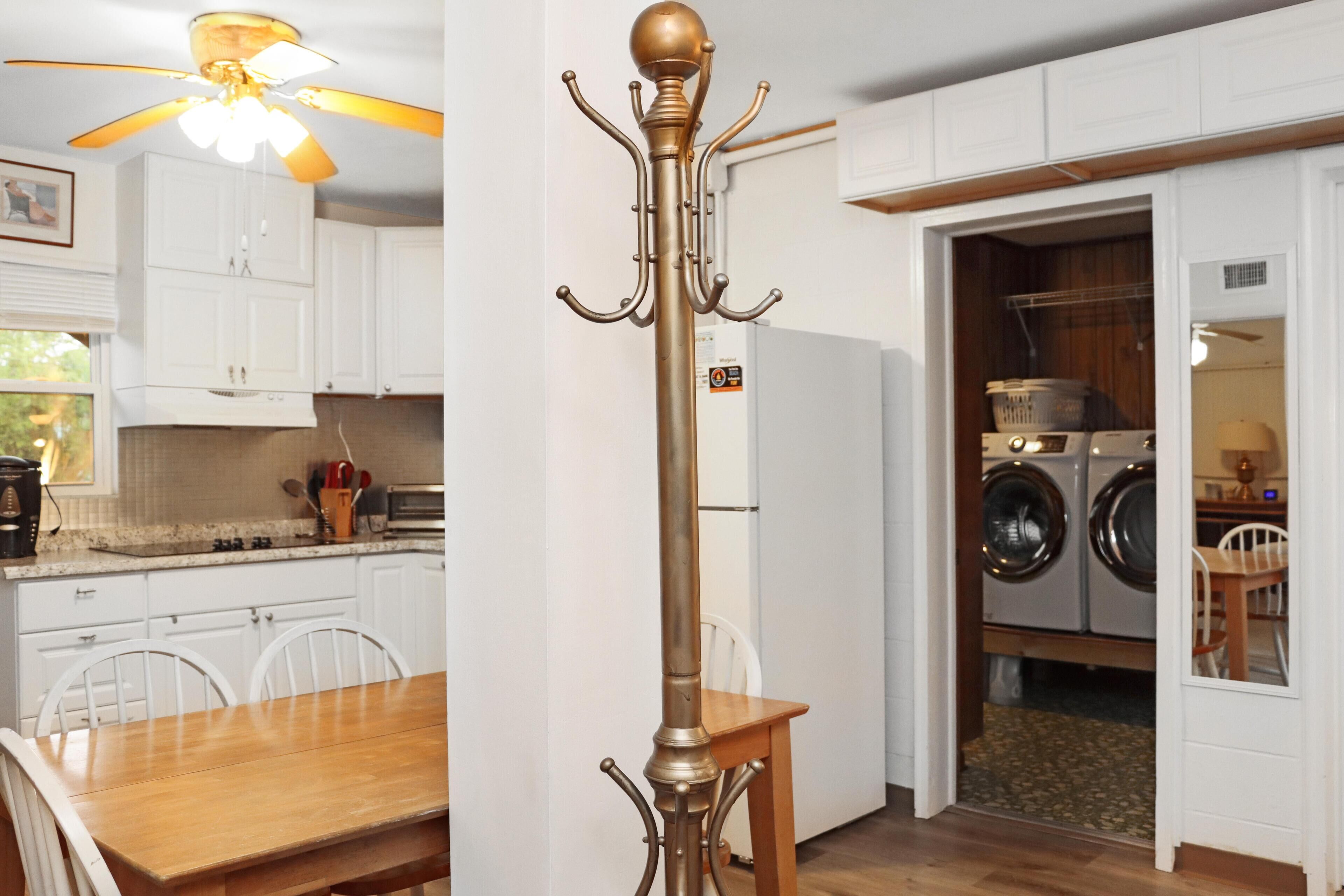 A kitchen with white cabinets, a wooden dining table, and a ceiling fan.