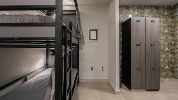 A dormitory room with bunk beds, a wardrobe, and a floral wallpaper.