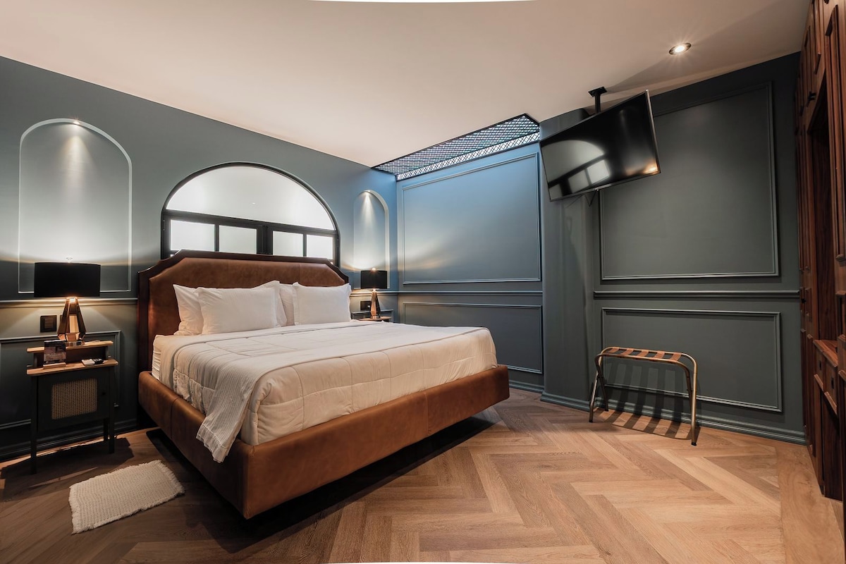 A modern bedroom with a large bed, a nightstand, a wall-mounted TV, and a unique ceiling design.