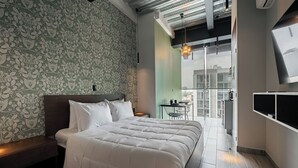 A modern bedroom with a large bed, a patterned wallpaper, a small table with chairs, and a view through a glass door. - Mr. Herold homes (Mexico City)