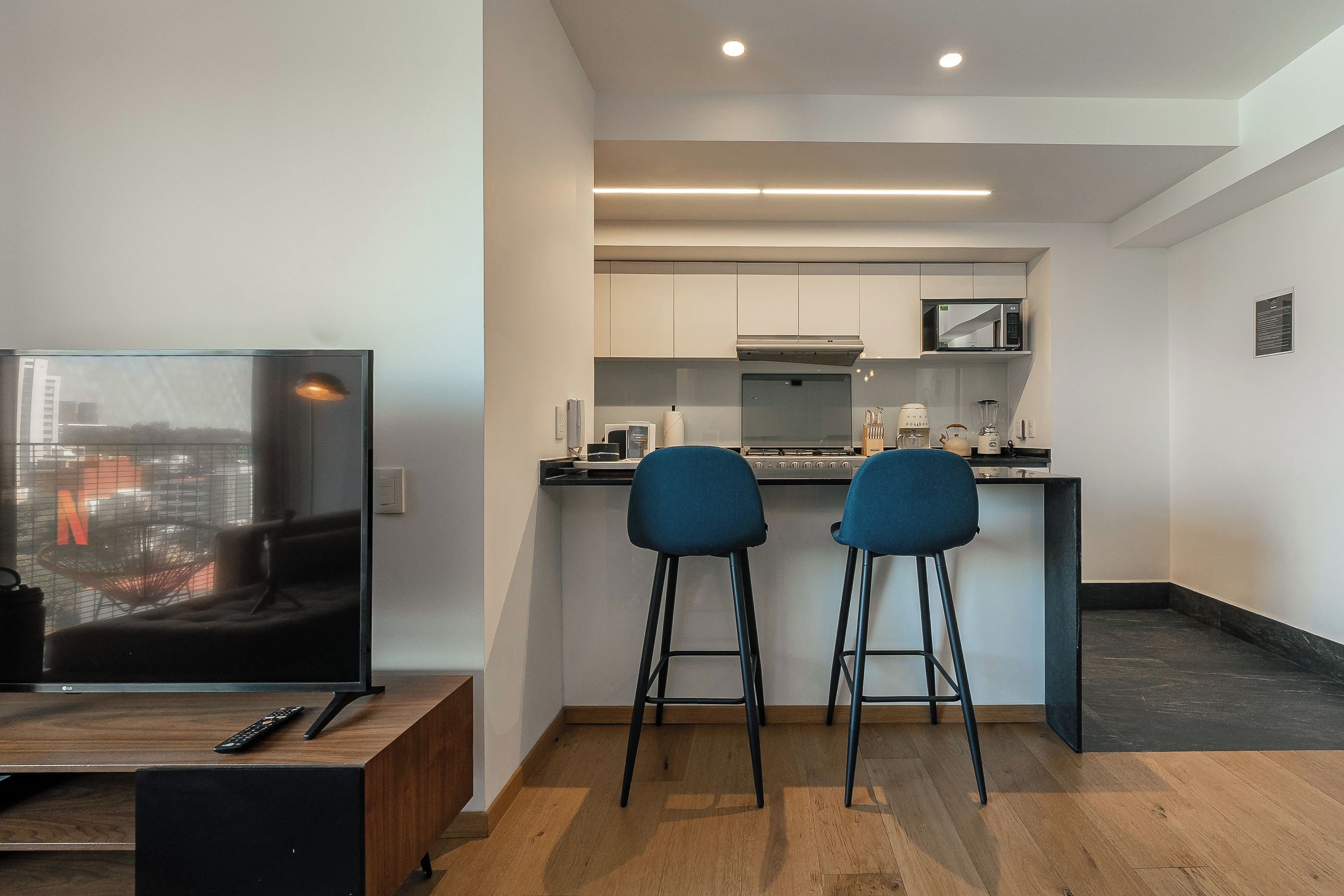 Une cuisine moderne équipée d’un four à micro-ondes, d’une cuisinière et de tabourets de bar.