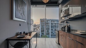 A modern kitchen with a dining area, large windows, and a view of high-rise buildings. - Mr. Herold homes (Mexico City)