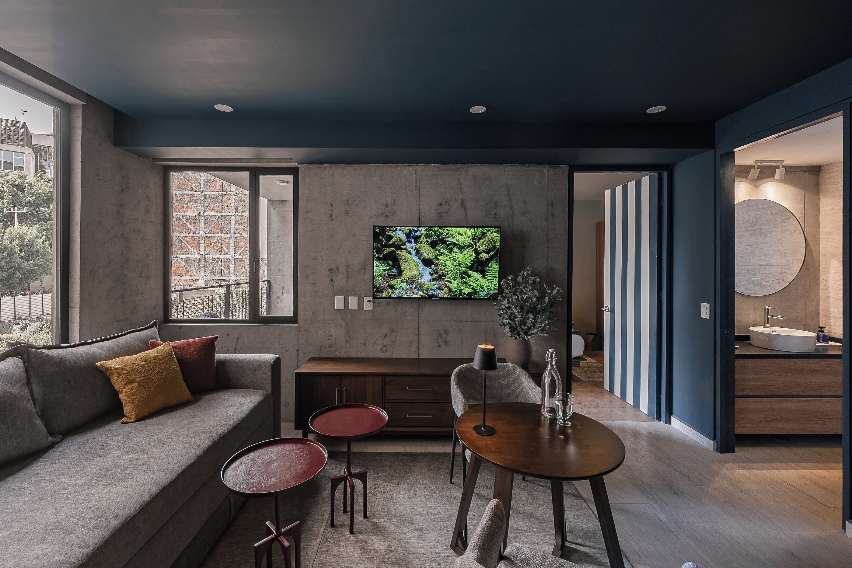 A modern living room with a sofa, a coffee table, and a TV mounted on the wall.