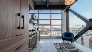 A modern kitchen with wooden cabinets, a bar area, and a large window offering a city view. - Mr. Herold homes (Mexico City)