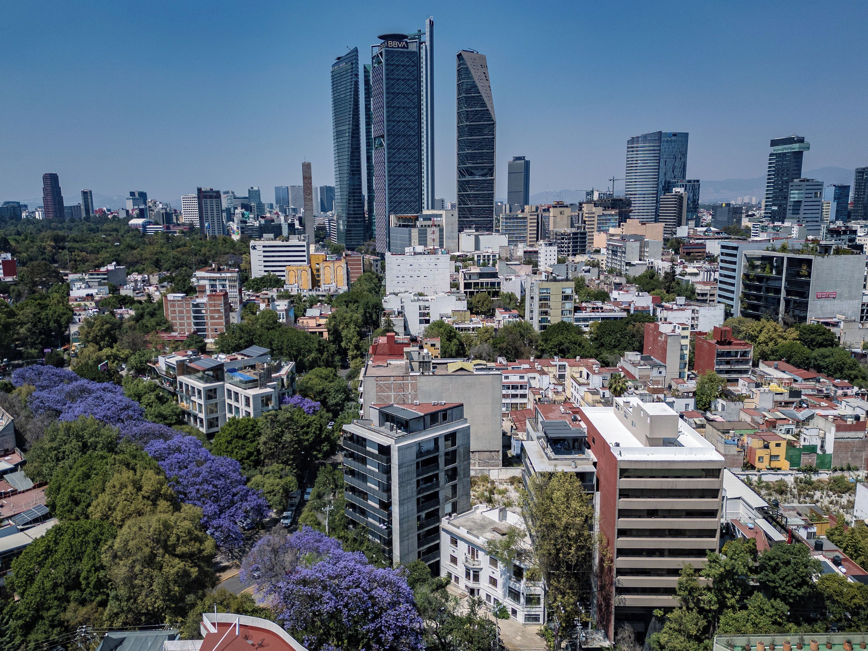 A cityscape with modern high-rise buildings, dense urban development, and surrounding greenery.