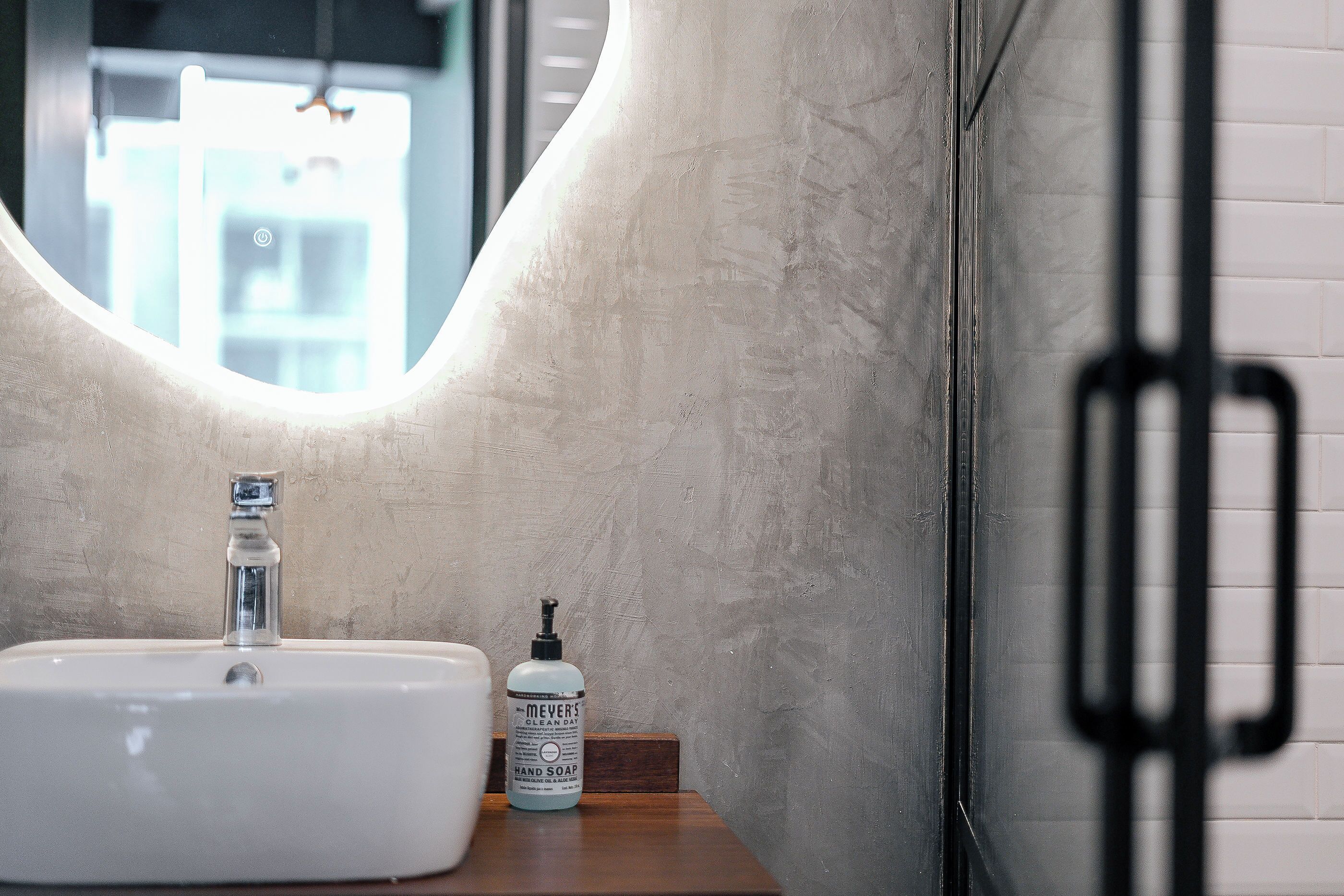 A bathroom with a white sink, a mirror, and a bottle of hand soap.