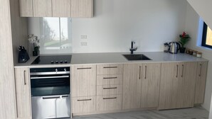 A modern kitchen with light wood cabinetry, a stainless steel oven, a sink, and a window providing natural light. - New House in New Brighton, Right by the Beach and Pier! (Christchurch)