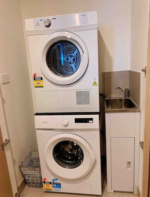 A stacked washer and dryer unit with a small sink and cabinet. - SkyGarden Luxury Apt | Mountain & Sunrise Views (Glen Waverley)
