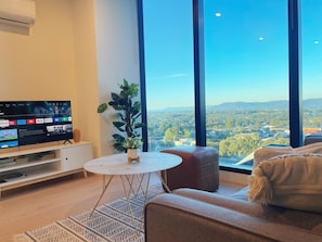 Una sala de estar moderna con un televisor grande, una mesa de centro redonda y un sofá.