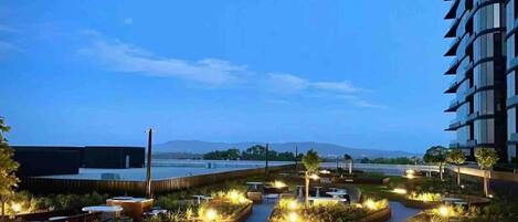 An outdoor terrace with seating areas, a water feature, and a view of the water body.