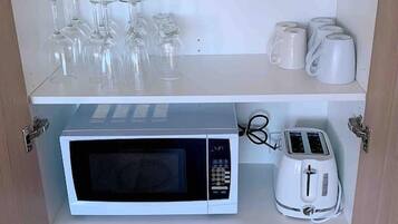 A kitchen with a microwave, toaster, and various glassware and dishes.