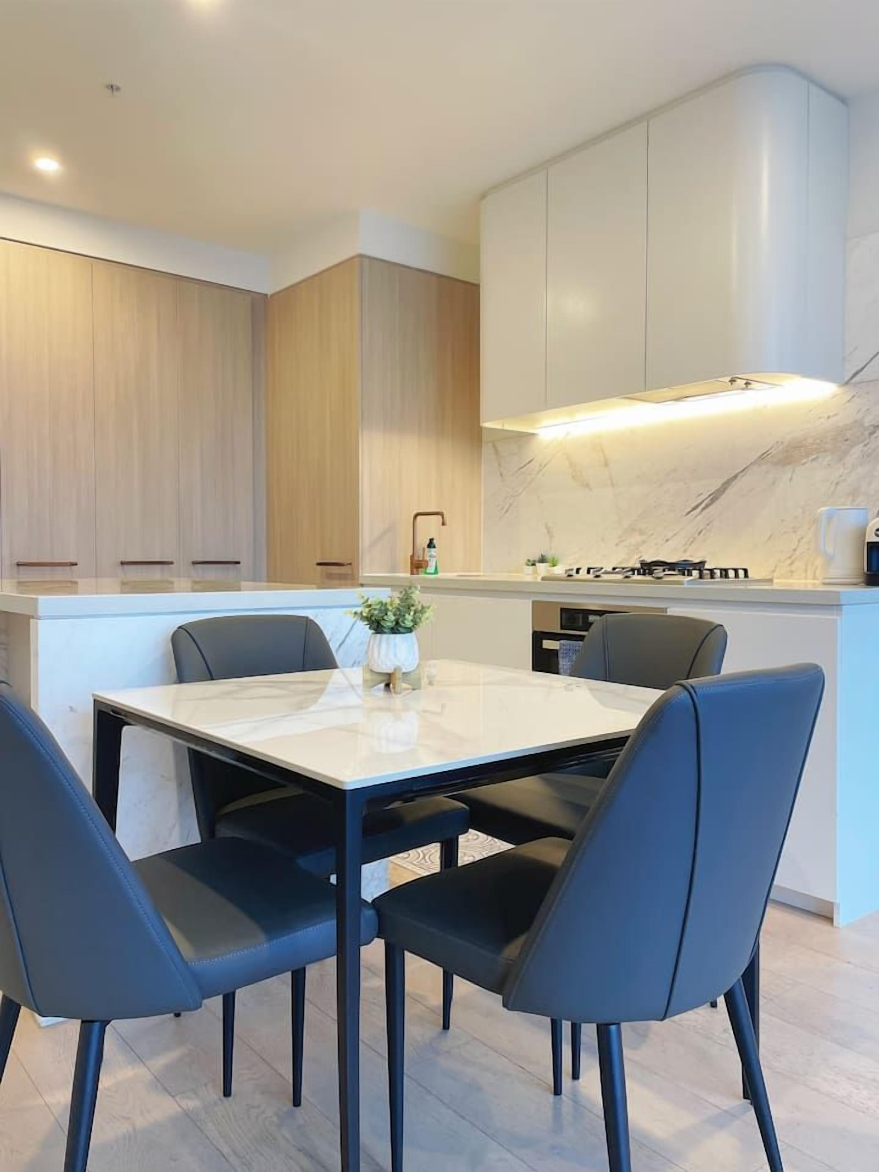 A modern kitchen with a marble countertop, built-in cabinets, and a central island with seating.