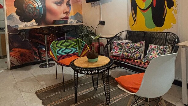 Una sala de estar moderna con un mural grande, una mesa redonda, un sofá y un televisor montado en la pared.