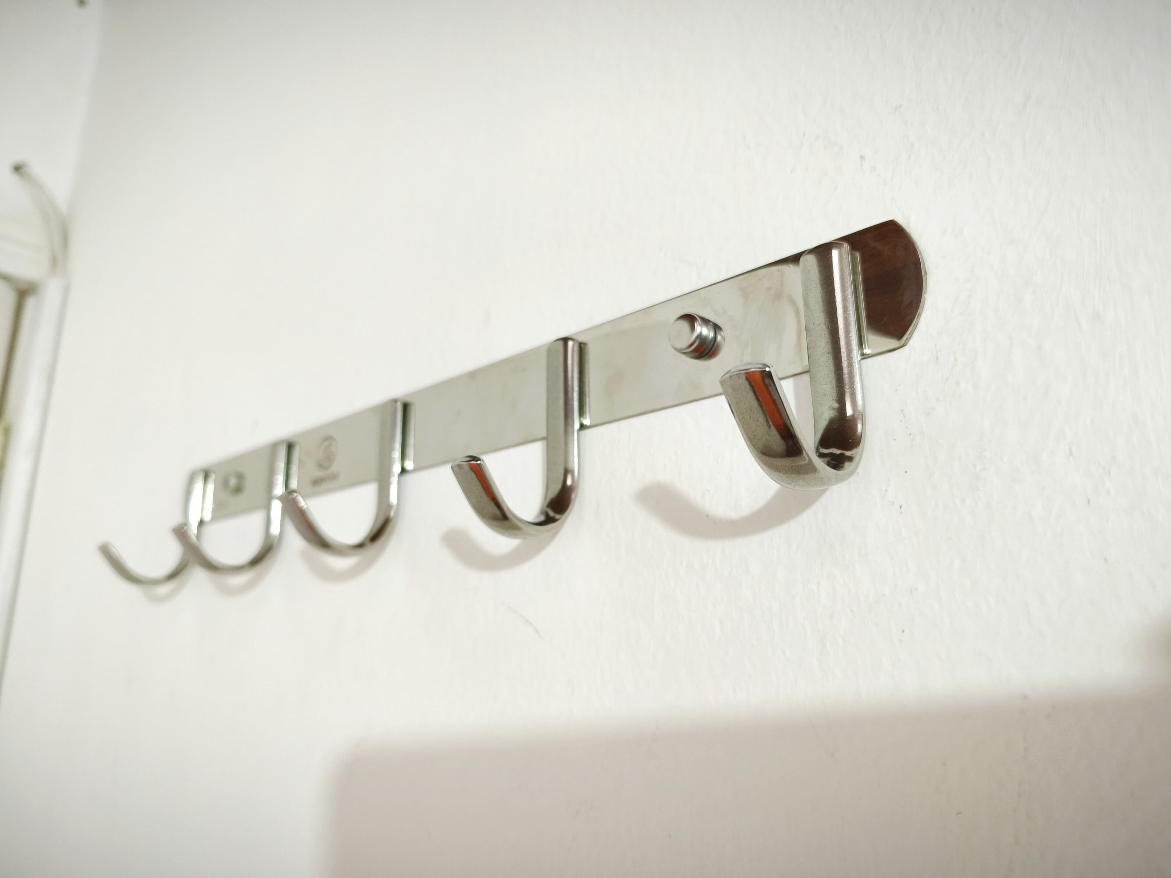 Ein Kleiderhaken aus Metall an einer weißen Wand.