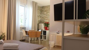 Une chambre d’hôtel équipée d’un lit, d’un bureau, d’une chaise, d’une télévision et d’une fenêtre avec des rideaux.