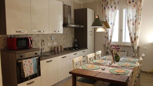 Une cuisine moderne avec des meubles blancs, un micro-ondes rouge et un coin repas comprenant une table et des chaises en bois.