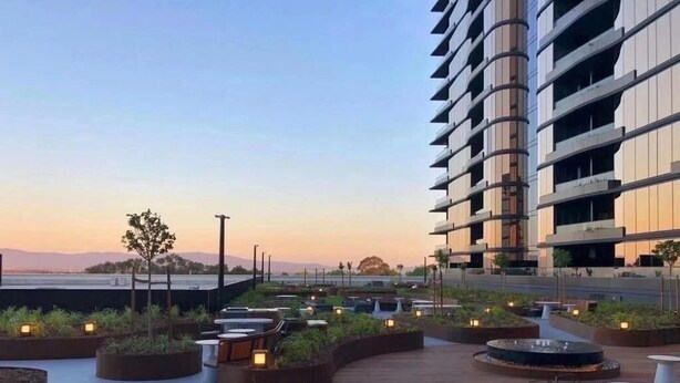 An outdoor terrace with seating areas, planters, and a view of a modern building. - Panoramic Views! Spacious 2 Bed, 2 Bath Luxury Apartment w/ Free Parking (Glen Waverley)